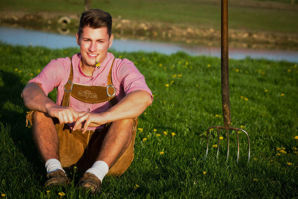 young blond bavarian man sitting in the grass - Foto, Imagem