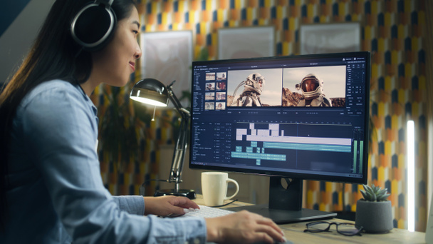Азиатка в гарнитуре редактирует видео с астронавтами для клиента в программе на персональном компьютере во время работы за столом из домашнего офиса. Фрилансер - Фото, изображение