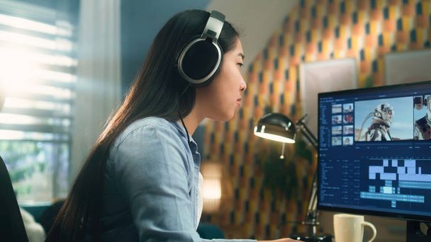 Азійська жінка в навушниках працює віддалено на pc з домашнього офісу і редагує відео з астронавтами для клієнтів у професійній програмі - Фото, зображення