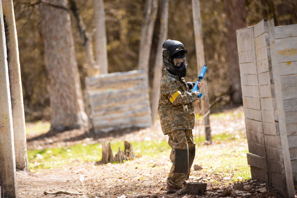a teenager with a machine gun and a paintball mask plays war - Foto, Imagen