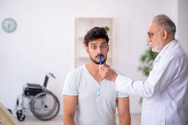 Paciente joven visitando viejo médico masculino - Foto, Imagen