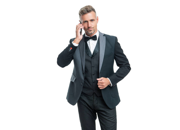 man in tuxedo speaking on smartphone isolated on white background. - Foto, Imagen