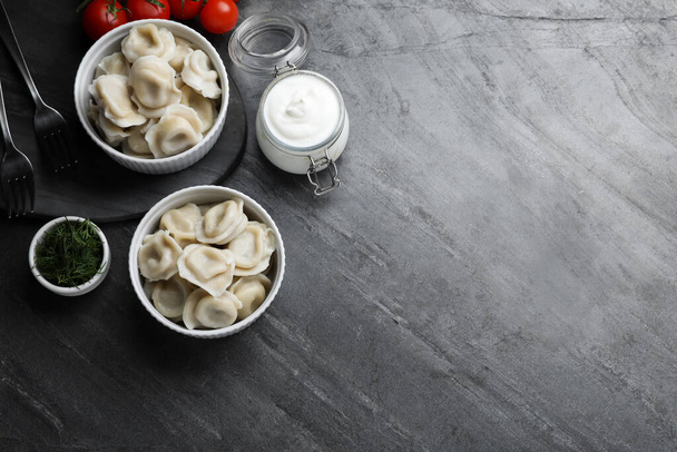 Tasty dumplings in bowls served on grey table, flat lay. Space for text - 写真・画像