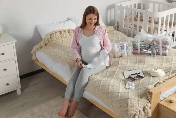 Schwangere packt Babysachen ein und bringt sie ins Entbindungskrankenhaus ins Schlafzimmer - Foto, Bild