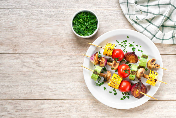 vegetable kebabs on skewers grilled on grill or BBQ  on a white plate, top view. Grilled vegetarian skewers of colorful vegetables. - Photo, Image