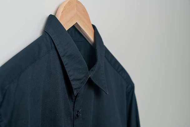 camisa negra colgante con percha de madera en la pared - Foto, imagen