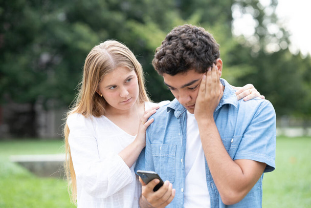 Латиноамериканец получает плохие новости по телефону и девушка утешает его. - Фото, изображение