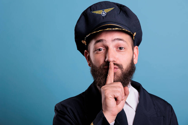 Airplane pilot showing silent gesture, looking at camera with forefinger on lips. Aviation academy plane captain front view, airforce aviator keeping secret, quiet, silence sign - Photo, Image