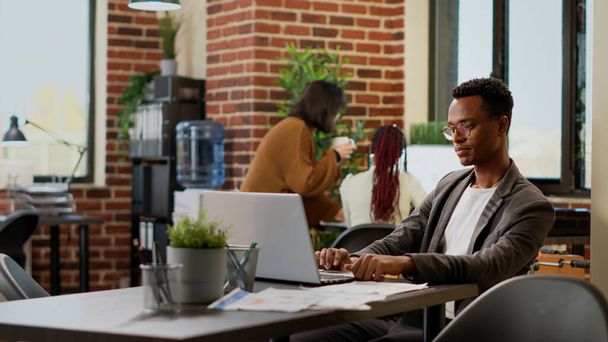African american man analyzing business data research on laptop, working on professional report to send email. Office worker brainstorming ideas to plan presentation project with charts. - Foto, Imagem