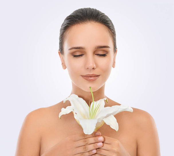 Perfecting perfection. Studio beauty shot of an attractive brunette woman holding a flower - Foto, Imagen