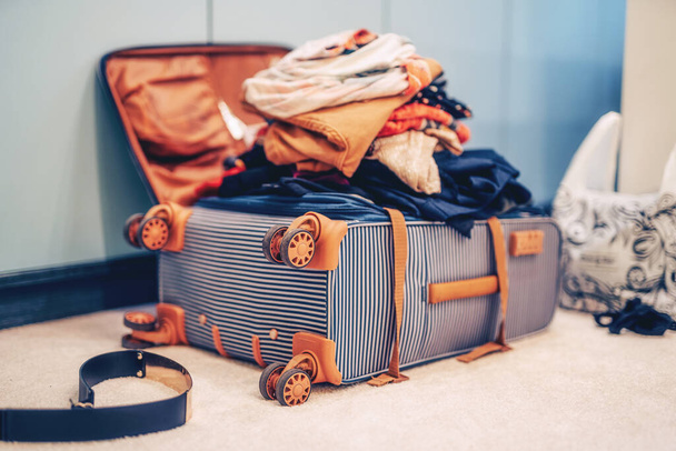 Открытый чемодан с одеждой в комнате - Фото, изображение