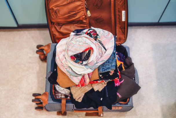 Offener Koffer voller Kleidung im Zimmer - Foto, Bild