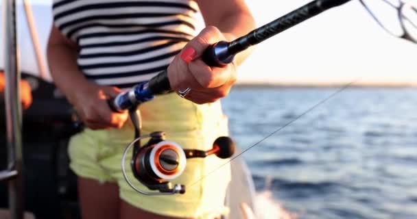 女性の手でボートから釣りのための釣りのタックルとリール。休暇中の観光客のための釣り - 映像、動画