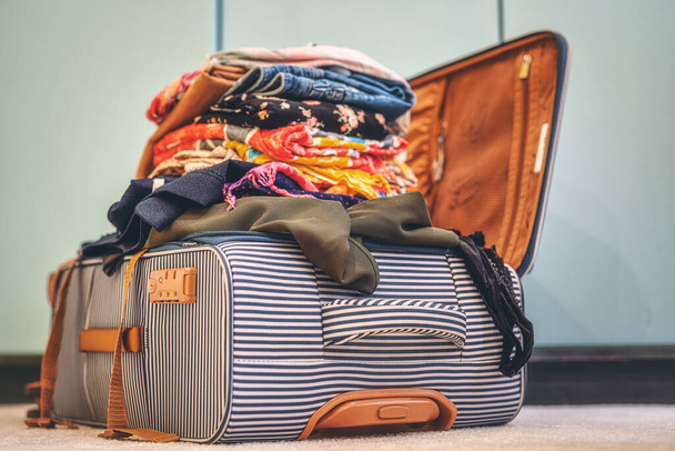 Open suitcase full of clothes in room - Foto, Imagem