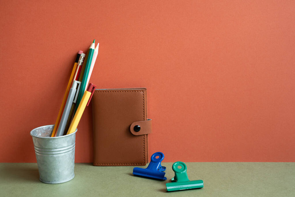 Notiz, Bleistifthalter, Clip am khakifarbenen Schreibtisch. roter Hintergrund. Arbeitsplätze, Bürobedarf - Foto, Bild