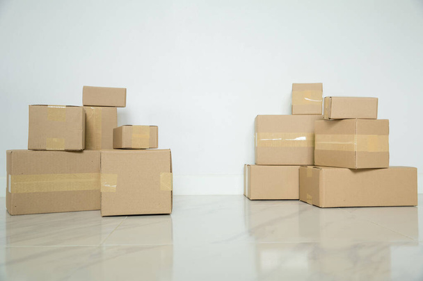 Stack of cardboard boxes for moving, Empty room with a white wall and cardboard boxes with unbranded barcode on the floor. Delivery of goods, shopping. Cardboard boxes on gray wall background. - Фото, зображення