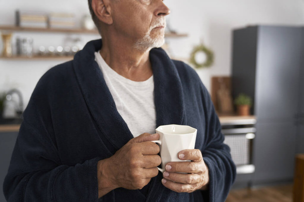 Primer plano del hombre mayor sosteniendo la taza de café en casa - Foto, imagen