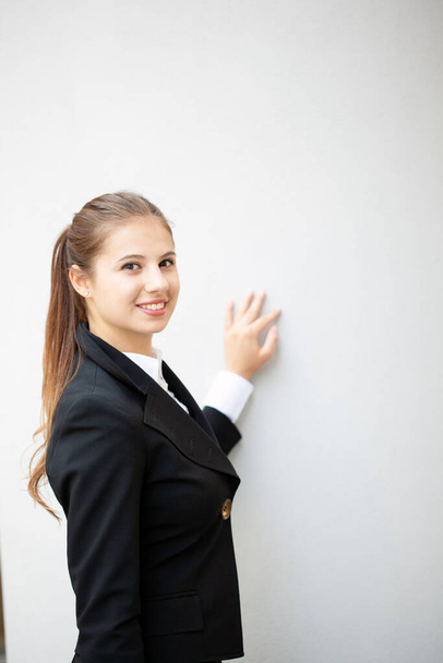 Portrait of a young smiling businesswoman near a wall - 写真・画像