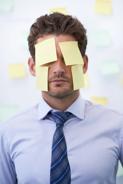Hiding from his responsibilities. a young businessman with a sticky notes covering his face - Fotografie, Obrázek
