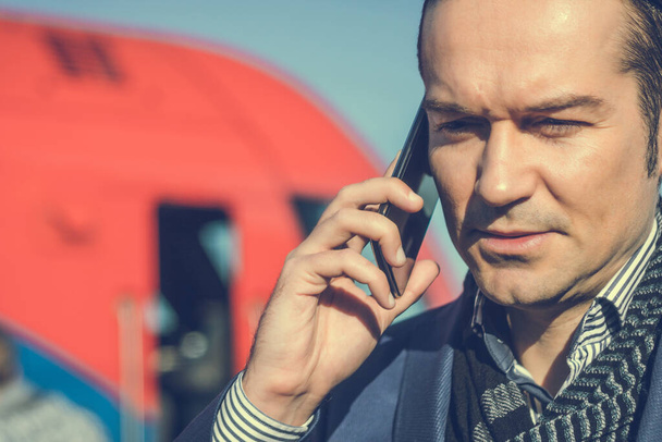Close-up van zakenman communiceren via mobiele telefoon op het station.  - Foto, afbeelding