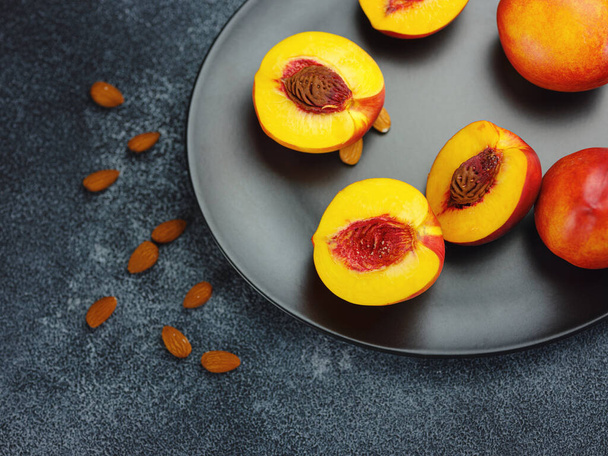 fresh sweet peaches and almond nuts on dark table. Fresh organic fruit Flat lay on old rustic background. Top view copy space - Foto, imagen