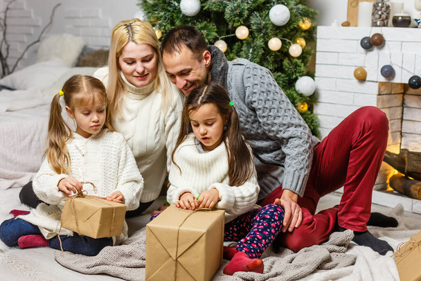 glückliche junge Familie hält Weihnachtsgeschenk und lächelt. - Foto, Bild