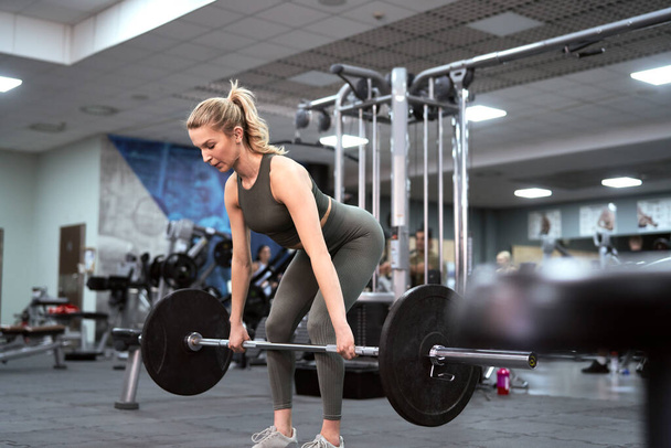 Caucasian woman training with barbells at the gym - Photo, Image