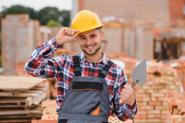 construction mason worker bricklayer installing red brick with trowel putty knife outdoors - Φωτογραφία, εικόνα