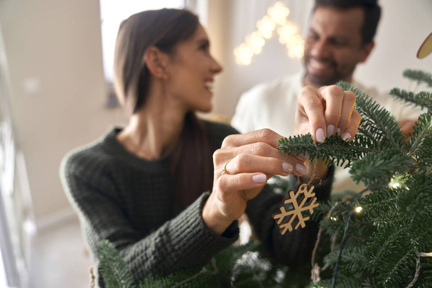 glückliches Paar schmückt Weihnachtsbaum zu Hause  - Foto, Bild