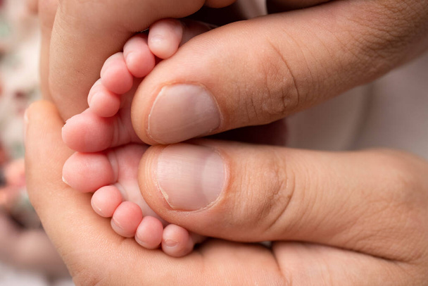 Mother and father are doing massage on her baby foot. Closeup baby feet in mother hands. Prevention of flat feet, development, muscle tone, dysplasia. Family, love, care, and health concepts.  - Фото, изображение