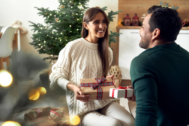 Multi ethnicity couple sharing Christmas present together at home - Fotoğraf, Görsel