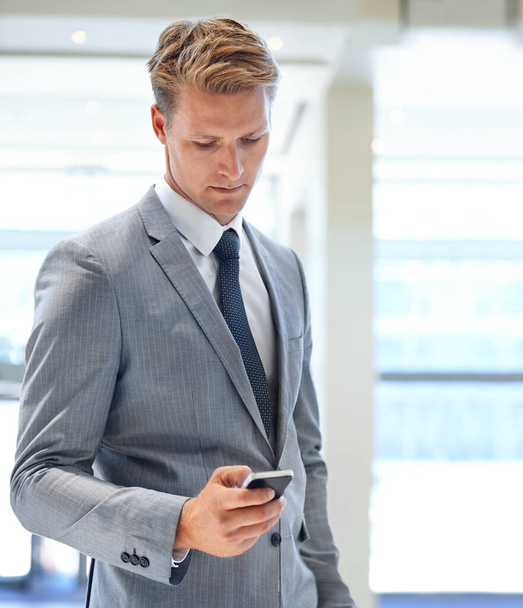 Keeping in touch with my clients. A handsome businessman sending a text message - Photo, Image