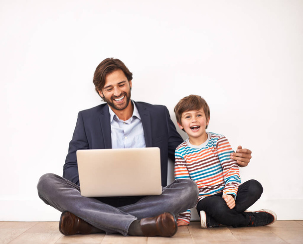 Gry komputerowe są zabawne w każdym wieku. Ojciec i syn siedzący na podłodze z laptopem - Zdjęcie, obraz