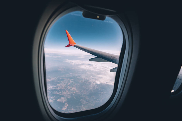 Вид крыла самолета из окна во время рейса на отдых или по делам. Красивое небо и изогнутое крыло для экономии топлива - Фото, изображение