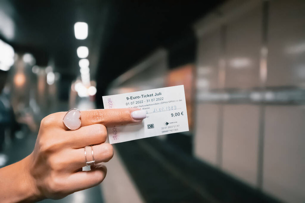 21 juli 2022, Düsseldorf, Duitsland: Een studente heeft een goedkoop kaartje van 9 euro in haar handen voor alle soorten vervoer in Duitsland voor een maand. Ondersteuning van ingezetenen van de overheid - Foto, afbeelding