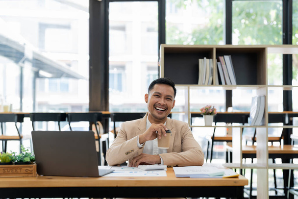 Ritratto di un bell'uomo d'affari esecutivo di successo intelligente guardando la fotocamera e sorridendo, felice nel moderno ufficio sul posto di lavoro - Foto, immagini