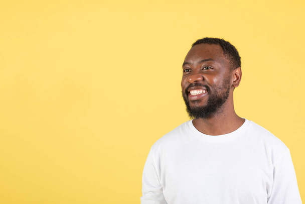 Portret Happy Black Guy pozowanie patrząc obok na wolne miejsce na reklamę tekstu Świetna oferta stoi nad żółtym tle Studio. Spójrz tam, Koncepcja banera reklamowego - Zdjęcie, obraz