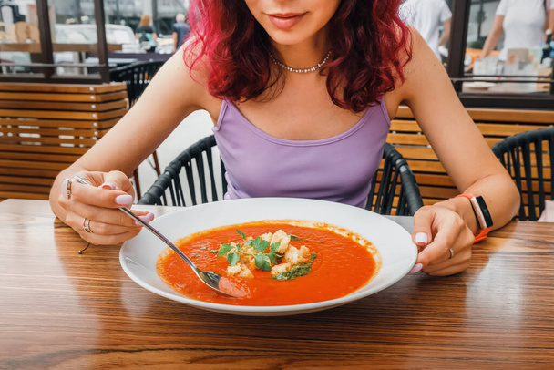 Mujer comiendo deliciosa sopa de tomate en cafetería o restaurante. Cocina vegetariana y dieta vegetal saludable. Cena y comida con productos ecológicos - Foto, Imagen