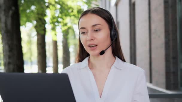 Obchodní žena nosit bezdrátové sluchátka s videokonference volání na notebook - Záběry, video