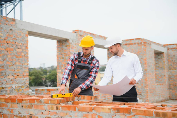 Structural engineer and foreman worker discuss, plan working for the outdoors building construction site. - Foto, imagen