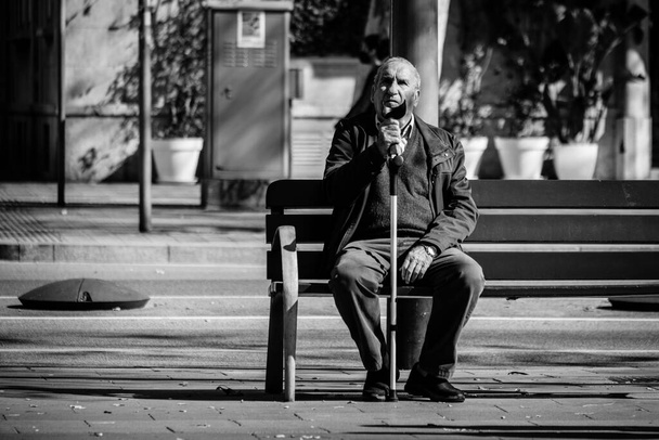 BARCELONA, HISZPANIA - LUTY 20, 2022: Człowiek z kulą spoczywa na ławce w parku miejskim. - Zdjęcie, obraz