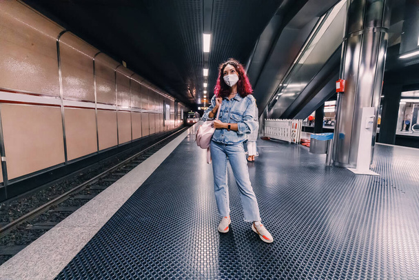 Une fille portant un masque médical de protection attend son train dans le métro pendant l'épidémie de coronavirus. - Photo, image