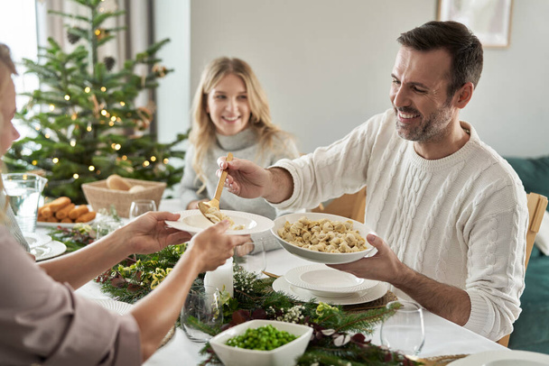 Blanke man die ravioli deelt op kerstavond   - Foto, afbeelding