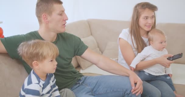 Jovens pais estão entretendo seus filhos e assistindo TV - Filmagem, Vídeo