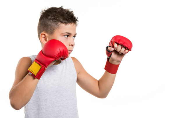 niño de karate en posición de lucha se concentra en sus manos guantes rojos, sobre un fondo blanco, aislar - Foto, Imagen
