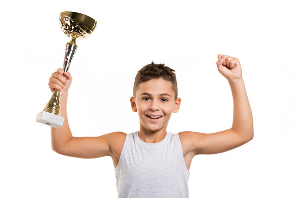 彼の手にスポーツカップを持つ少年,彼の手と笑顔を上げました,勝利の喜び,白い背景に,コンセプト,隔離 - 写真・画像