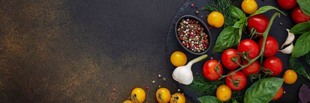 Ruokabanneri, tuoreet kypsät punaiset ja keltaiset tomaatit, mausteet ja basilikan lehdet, valkosipuli ja vihreät sipulit pimeällä pöydällä, terveellisen ruoan konsepti, kopiotila, ylhäältä - Valokuva, kuva