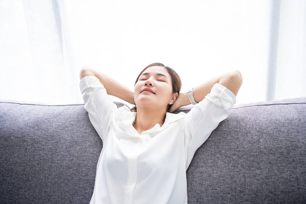 Giovane donna asiatica sedersi rilassarsi sul divano in soggiorno. Sta dormendo o sta riposando per alleviare le emozioni negative. - Foto, immagini