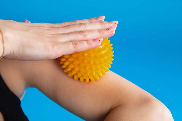 girl athlete holds in her hand a yellow massage ball with spikes, massages the forearm, close-up shot - Zdjęcie, obraz