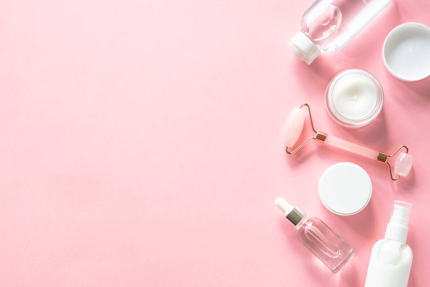 Skin care product, cream, soap serum, jade roller. Natural cosmetics on pink. Flat lay image with copy space. - Photo, Image
